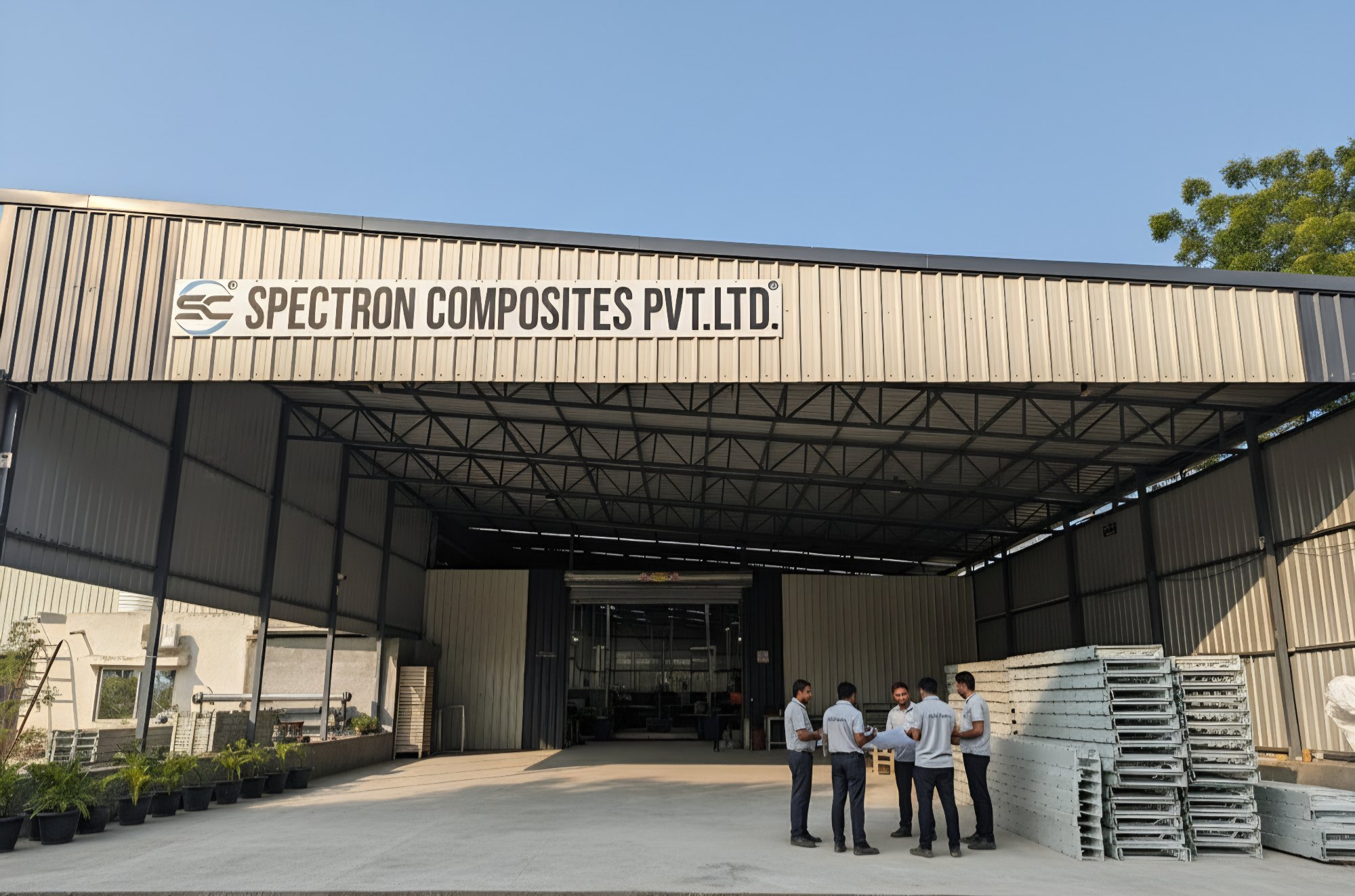 The Spectron Composites plant at Por GIDC, Vadodara — staff outside the main shed with FRP gratings stacked alongside
